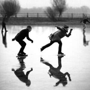 Skaters on ice reflecting in water, outdoor winter activity at the ice rink.